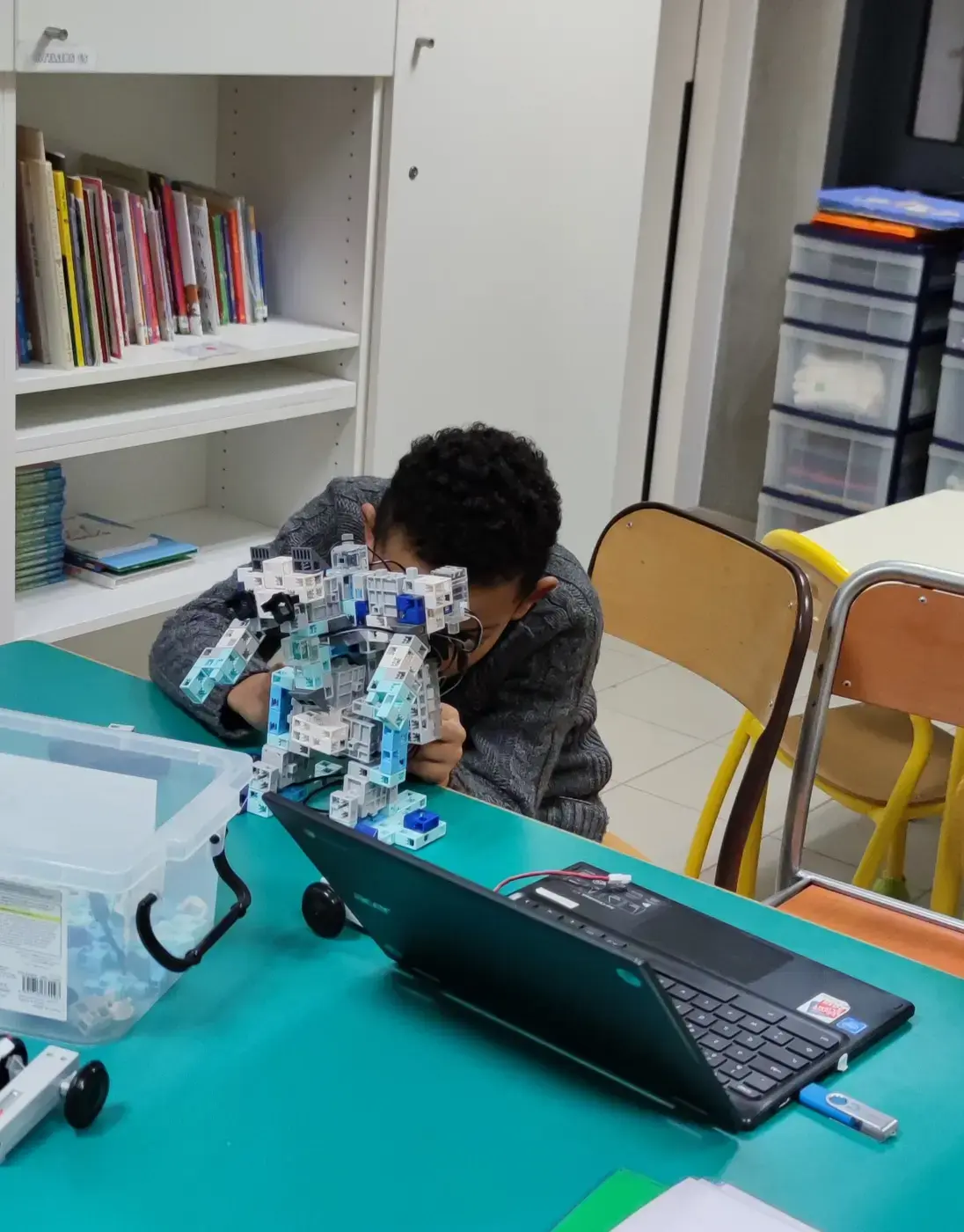 Un participant assemble avec attention une construction robotique devant son ordinateur.