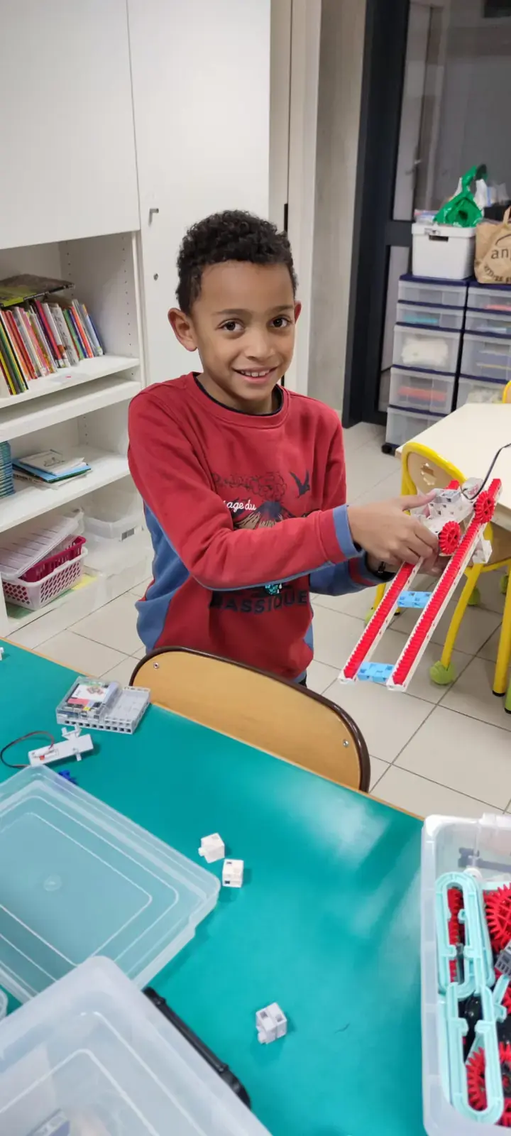 Un enfant présente une construction robotique réalisée en atelier.